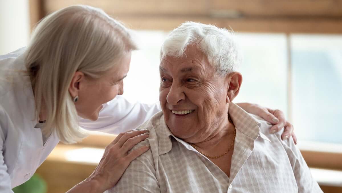 eine Mitarbeitende von Vitassist kümmert sich, im Rahmen einer Demenzbetreuung, einfühlsam um einen älteren Herr