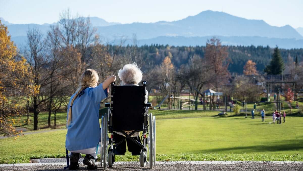 eine Rentnerin geniesst, dank ihrer Ferien- und Reisebegleitung, den Blick auf die Berge
