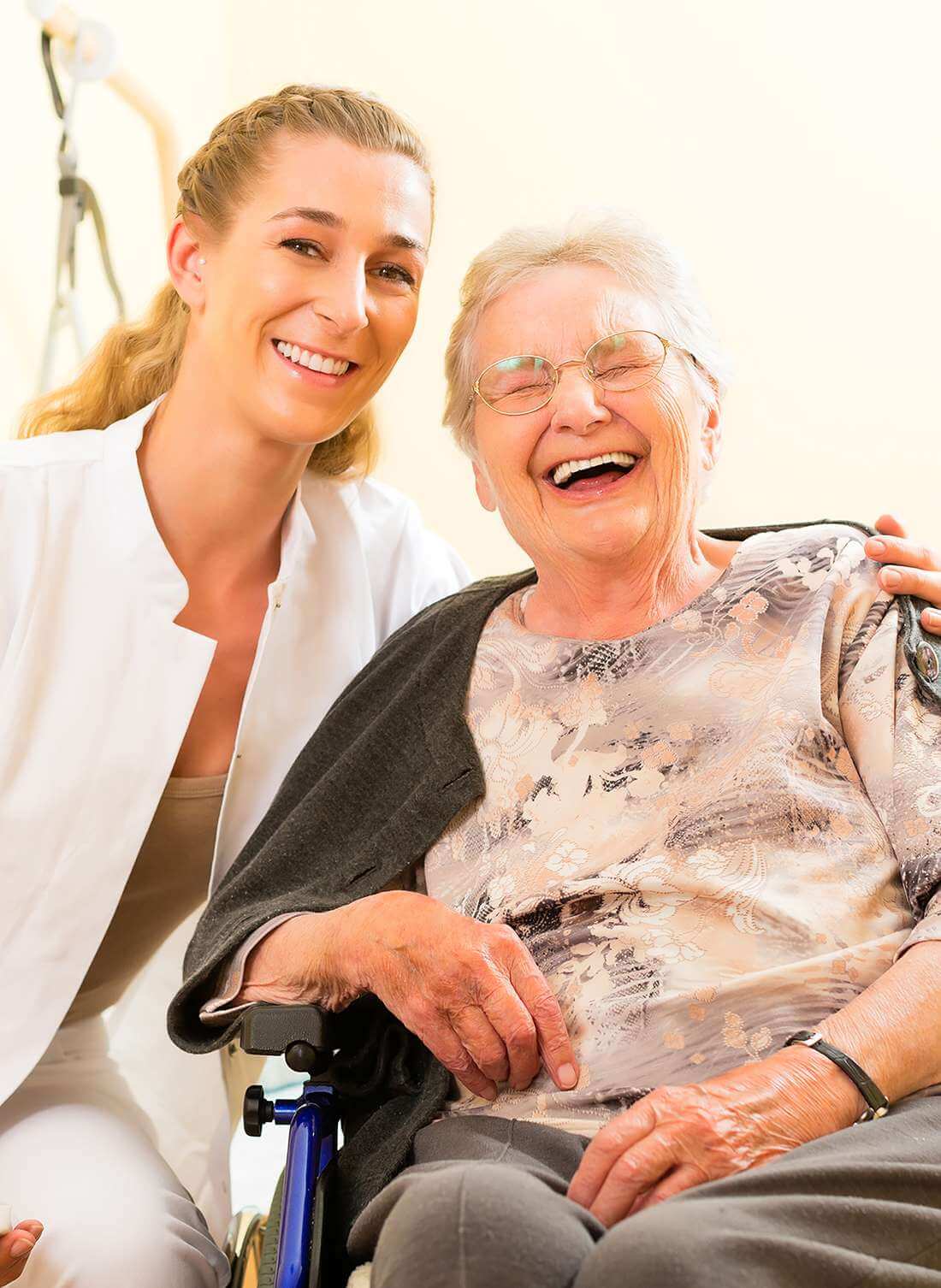 Rentnerin im Rollstuhl lacht gemeinsam mit ihrer Betreuerin in ihrem Zuhause in Brugg.