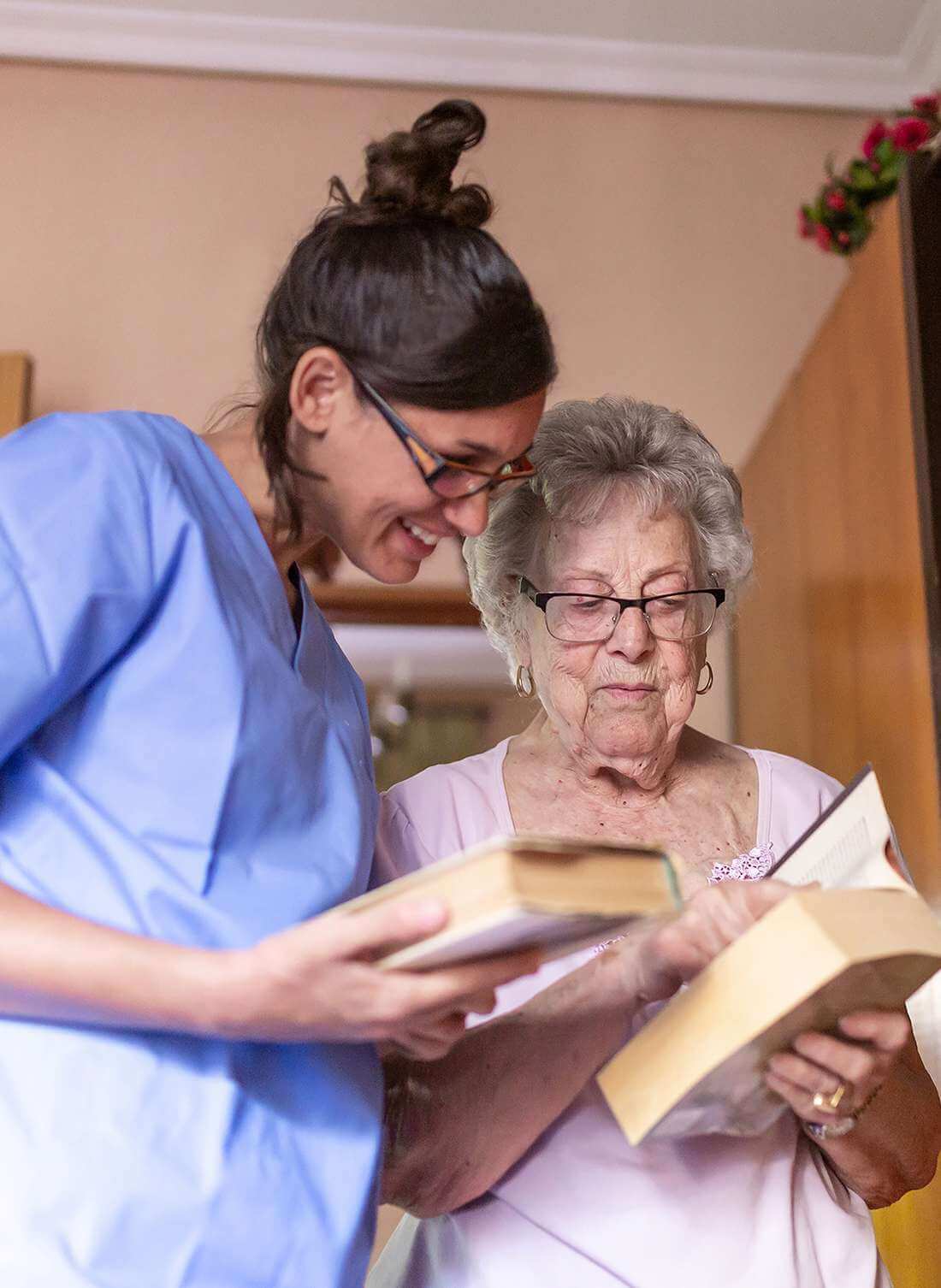 Seniorin mit ihrer Betreuerin zu Hause in Hochdorf beim Lesen eines Buches.
