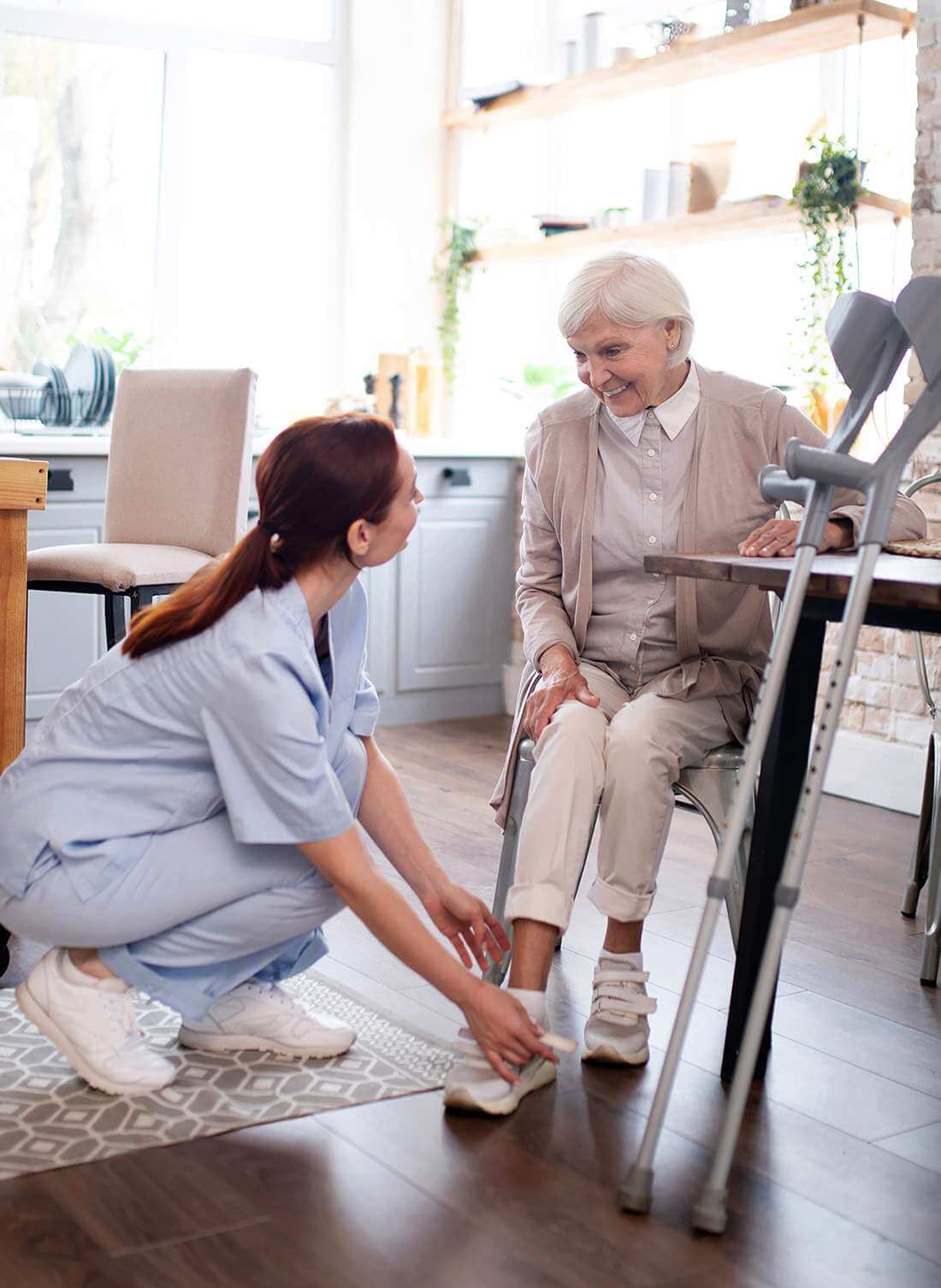 Rentnerin lächelt dankbar, während eine Pflegerin der Spitex Thal ihr die Schuhe schnürt.