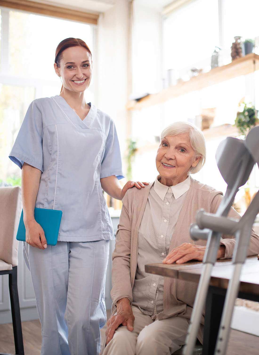 Vergnügte Rentnerin sitzt neben ihrer Betreuerin und freut sich über die Gesellschaft in ihrem Zuhause in Zurzach.