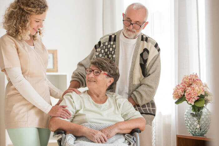 Rentnerpaar mit ihrer Pflegerin im vertrauten Zuhause, dank den Leistungen von Vitassist.